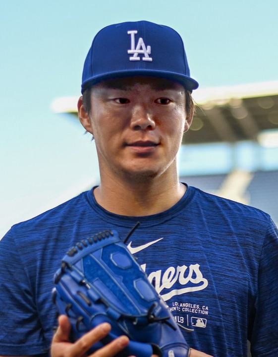 Yoshinobu Yamamoto in a Dodgers cap and warm-up shirt, holding his glove